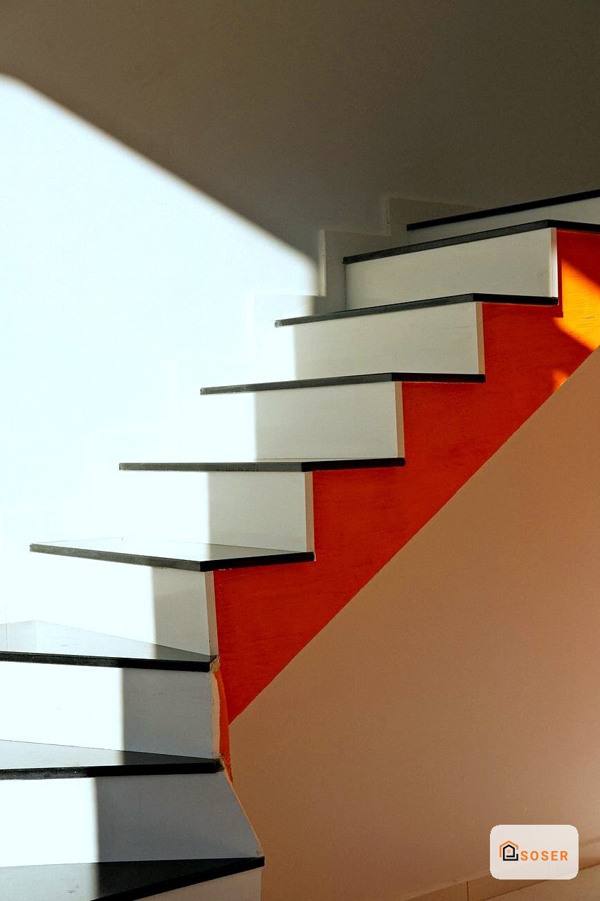 Scala moderna con gradini bianchi e struttura metallica nera su parete rossa, design contemporaneo