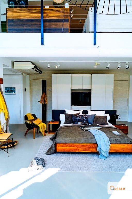 Loft moderno con letto arancione, zona living e soppalco in stile industriale con finiture in cartongesso