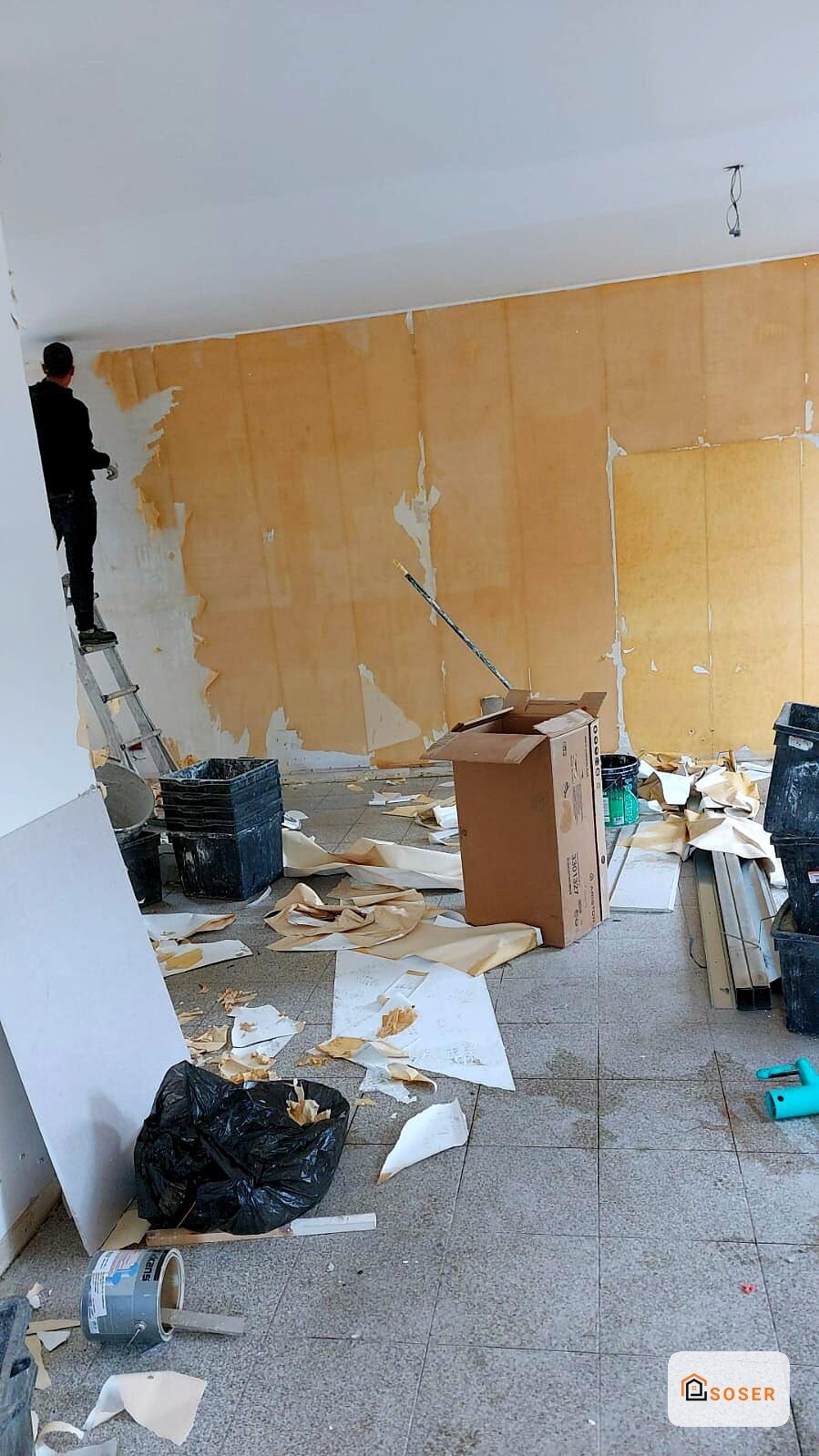 Demolizione interna con cartongesso rimosso, pareti gialle e materiali di scarto in cantiere