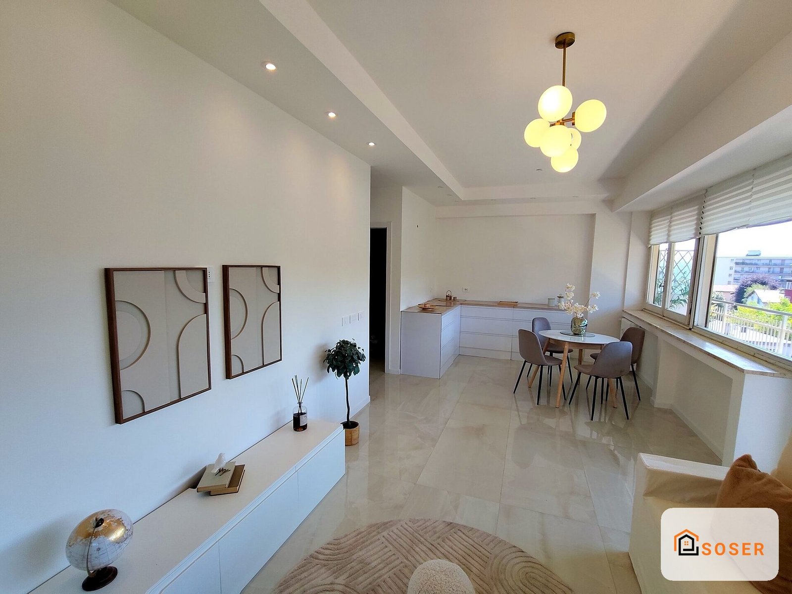 Cucina e soggiorno moderni con pavimenti in marmo, mobili bianchi e illuminazione a sospensione