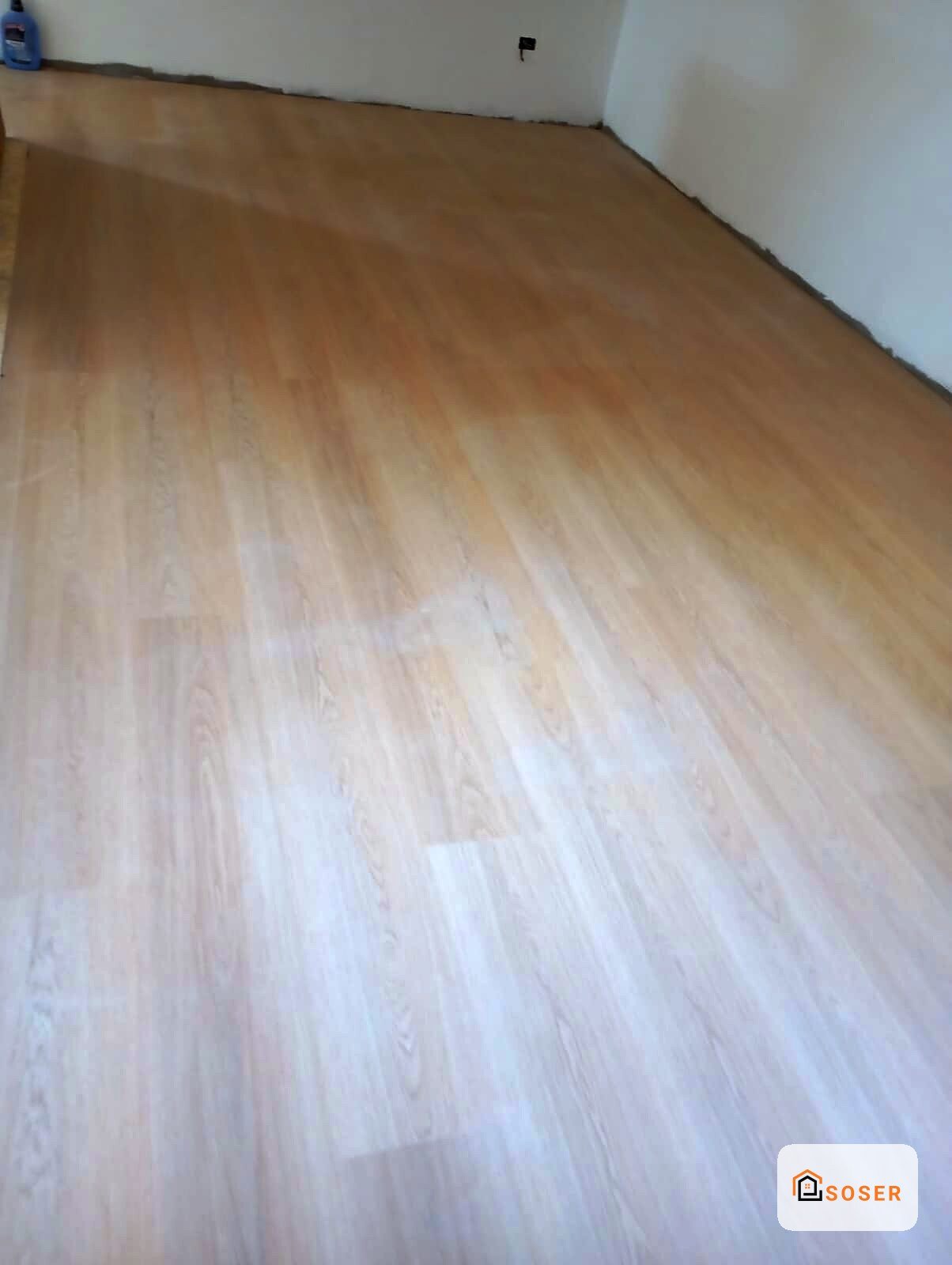 Pavimento in laminato effetto legno chiaro in stanza vuota con pareti bianche