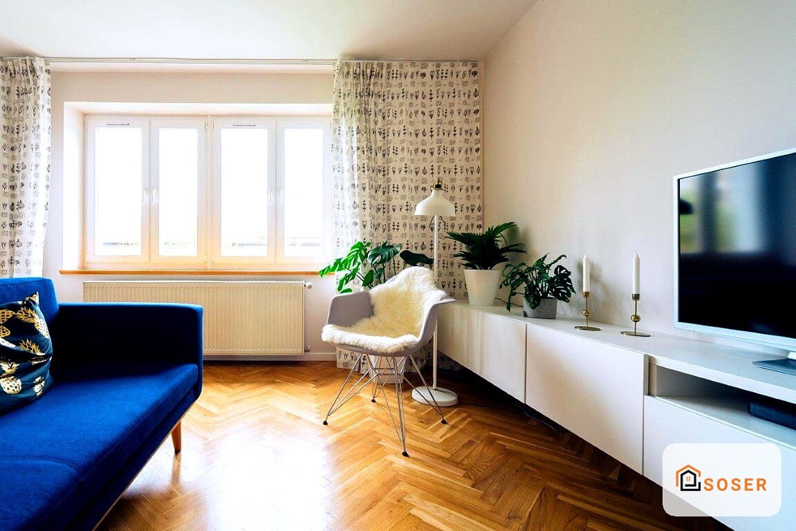 Soggiorno moderno con divano blu, pavimento in parquet e parete con carta da parati geometrica