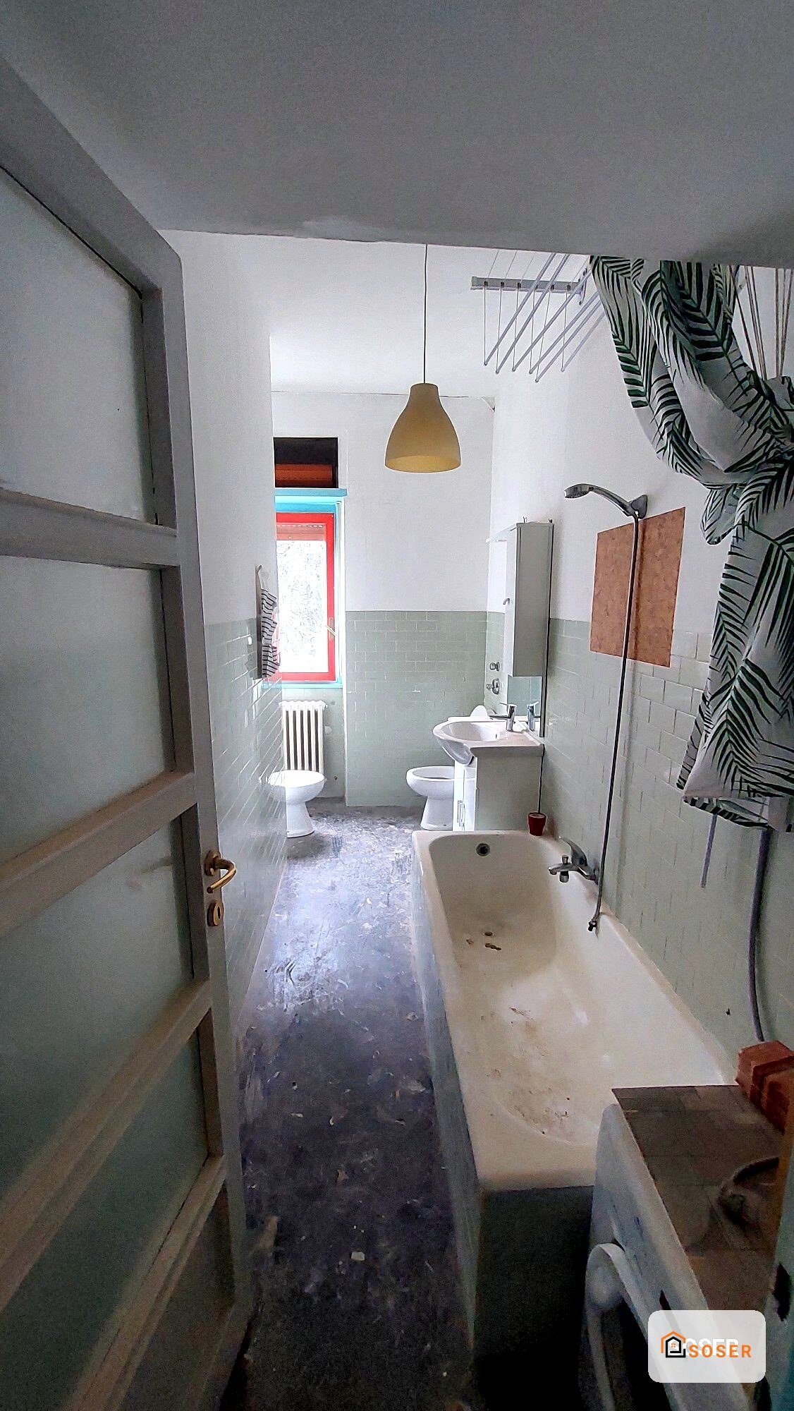 Bagno in ristrutturazione con vasca, sanitari e piastrelle bianche, prima della rifinitura