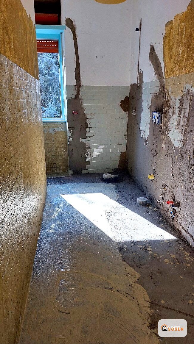 Bagno in ristrutturazione con pareti umide, muffa e danni, prima dei lavori di restauro