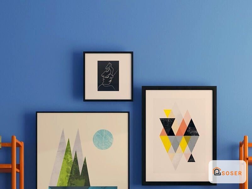 Parete blu con tre quadri incorniciati in stile minimalista e moderno con decorazioni geometriche