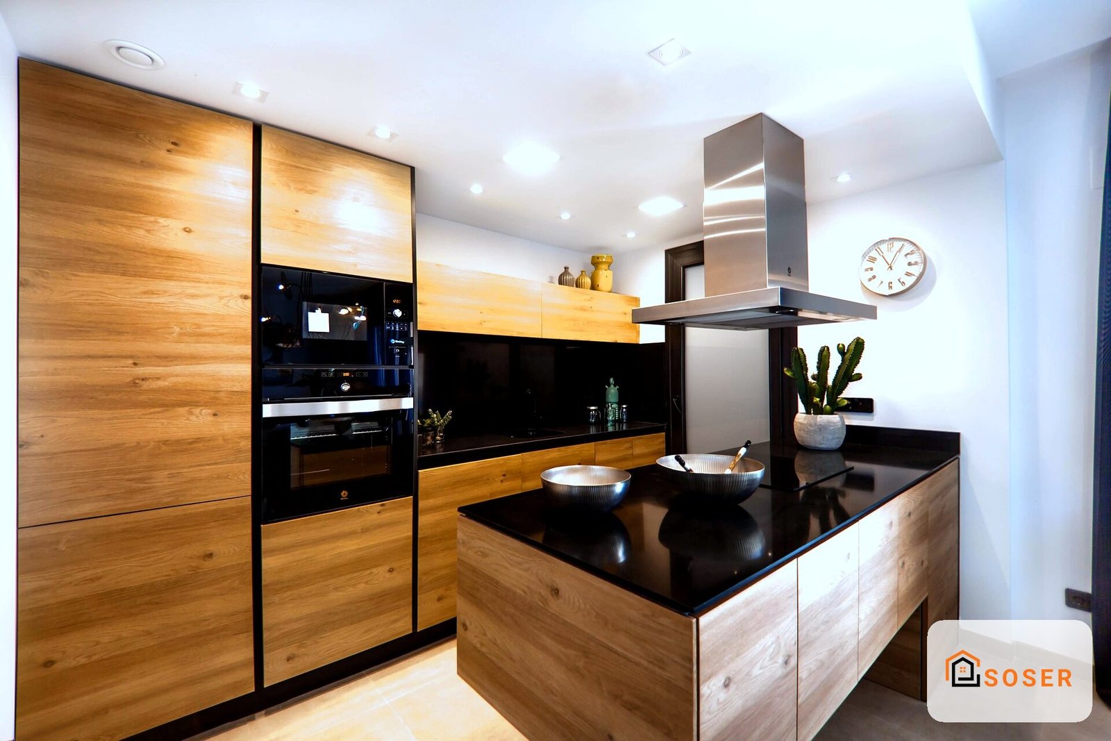 Cucina moderna con mobili in legno naturale, isola centrale con top nero e cappa acciaio inox