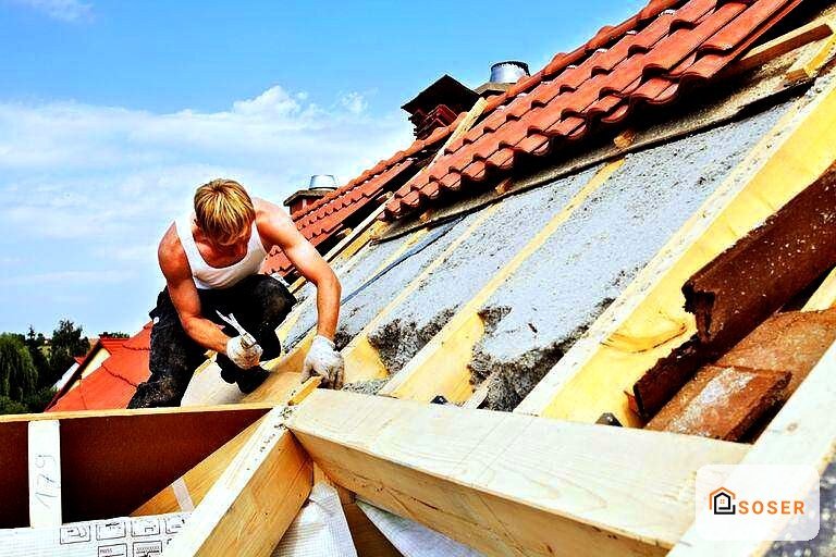 Operaio esegue lavori di ristrutturazione del tetto con isolamento termico e copertura in coppi