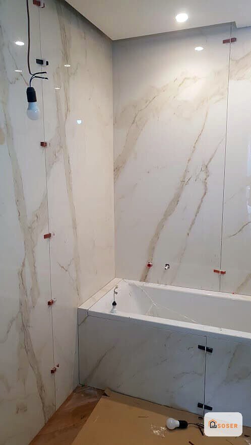 Bagno moderno in ristrutturazione con rivestimento in marmo bianco e vasca da bagno