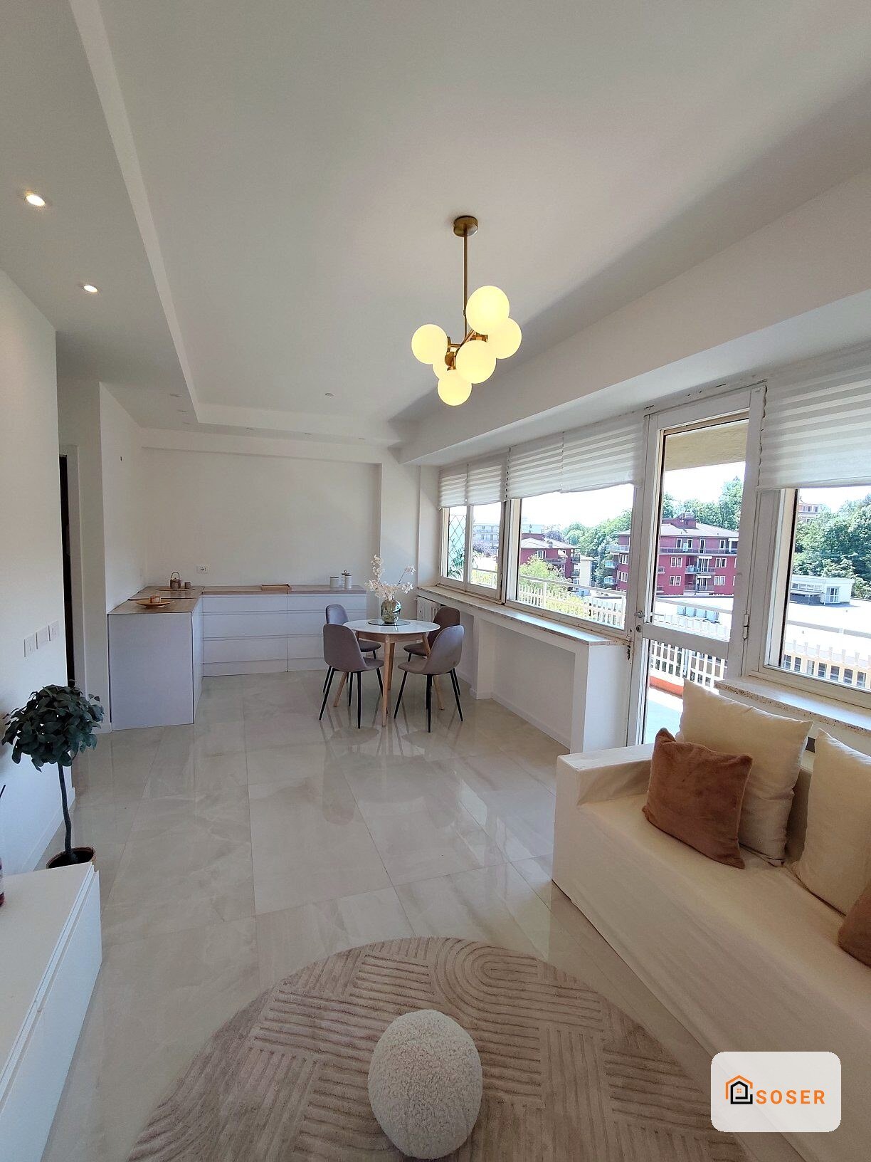 Soggiorno moderno con cucina a vista, pavimenti in marmo, divano beige e grandi finestre panoramiche