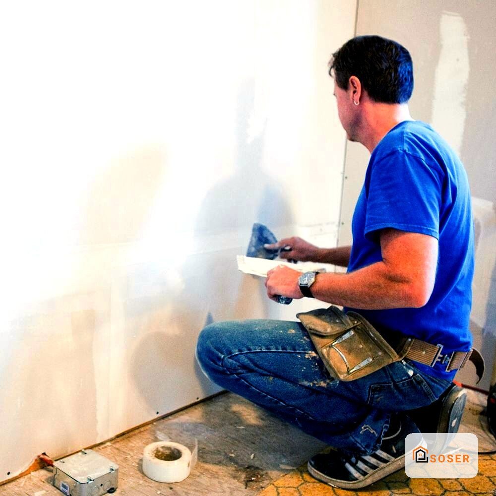 Operaio applica stucco su parete in cartongesso durante lavori di ristrutturazione