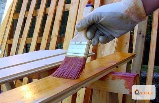 Applicazione di vernice su legno con pennello durante lavori di finitura e imbiancatura