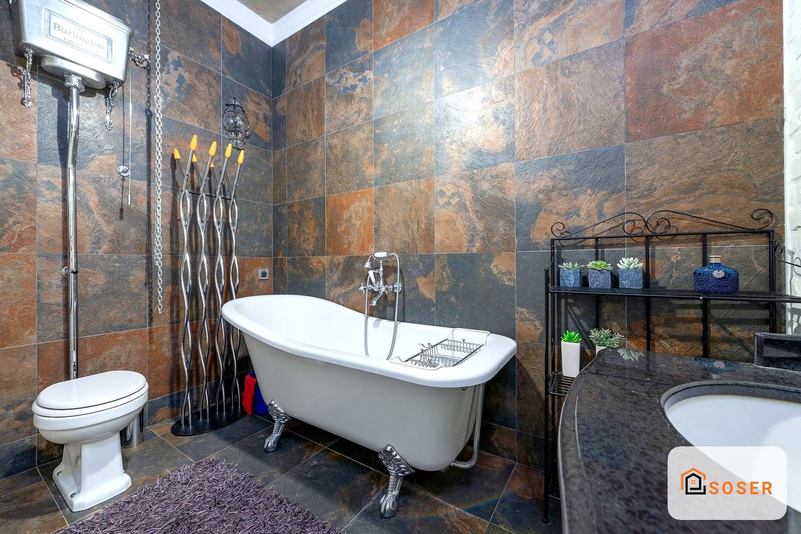 Bagno lussuoso con vasca freestanding bianca, piastrelle in ardesia marrone e grigio, sanitari moderni e arredo decorativo