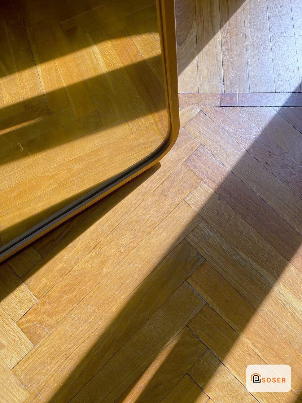 Pavimento in legno con parquet a spina di pesce e finestra che crea giochi di luce