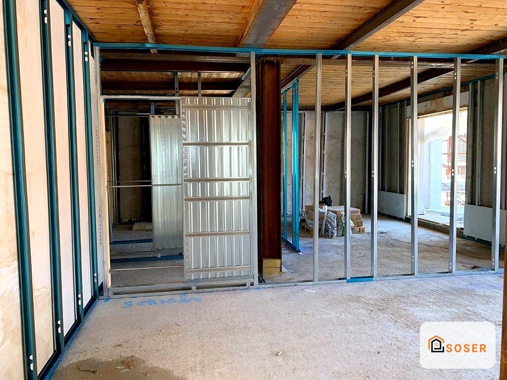 Interno di edificio in ristrutturazione con struttura in legno, infissi in alluminio blu e pareti in cartongesso