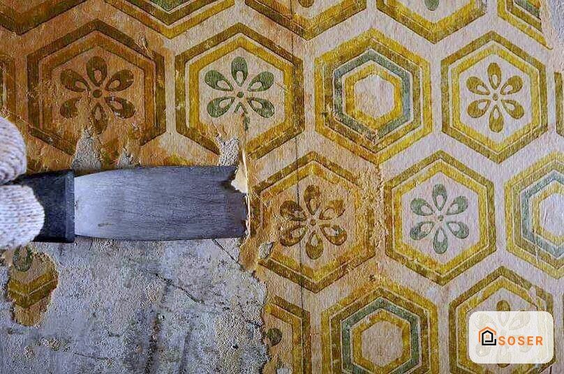 Pavimento in mosaico con pattern geometrico esagonale e decorazioni floreali, parzialmente coperto da nastro protettivo durante i lavori