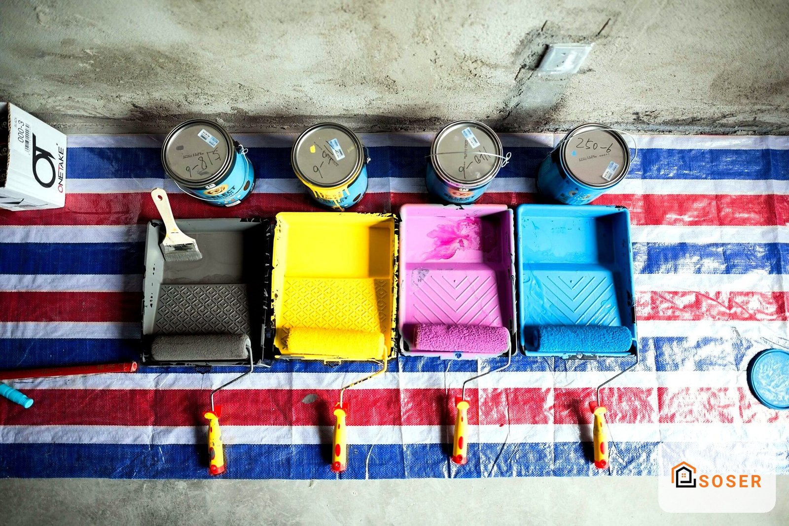 Preparazione imbiancatura con rulli colorati e barattoli di vernice su strisce blu e rosse