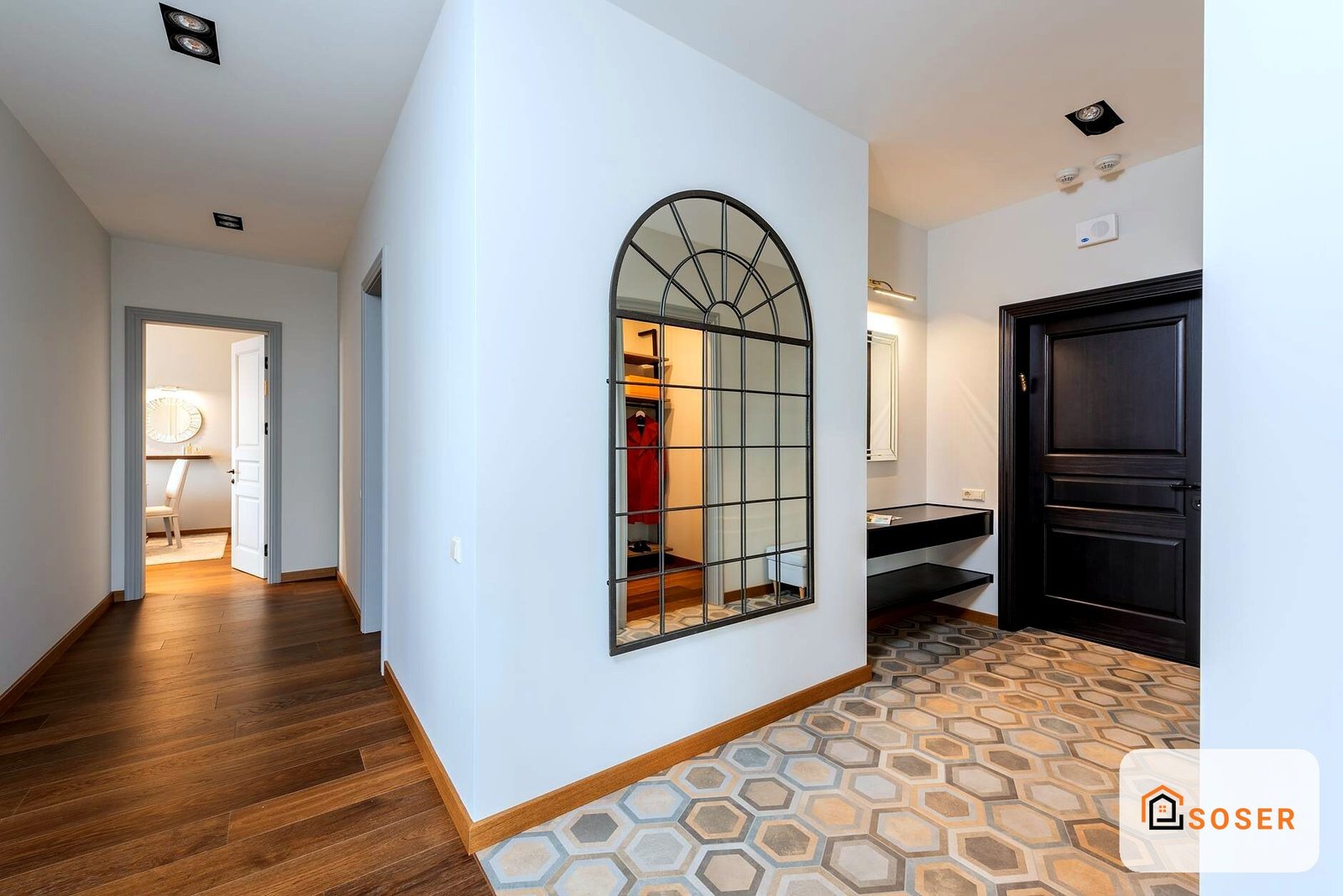 Corridoio moderno con pavimento geometrico, specchio ad arco e porte nere in abitazione ristrutturata a Milano