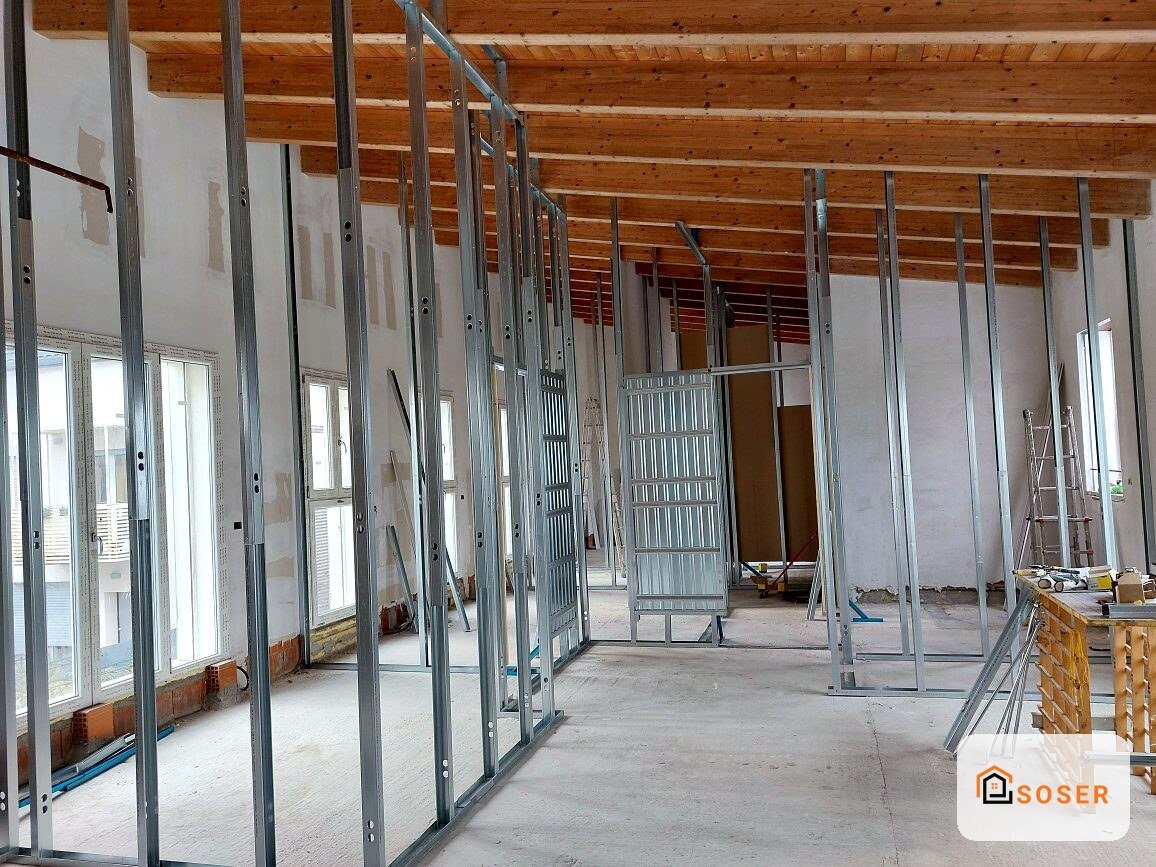 Interno in costruzione con struttura in cartongesso e infissi in alluminio, soffitto in legno a vista