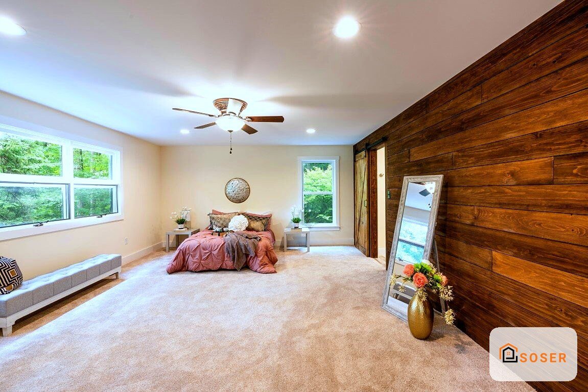 Moderna camera da letto con pareti in legno, ampio tappeto beige e finestre panoramiche con vista giardino