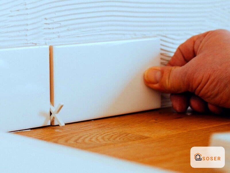 Installazione di battiscopa in legno su pavimento laminato durante lavori di ristrutturazione