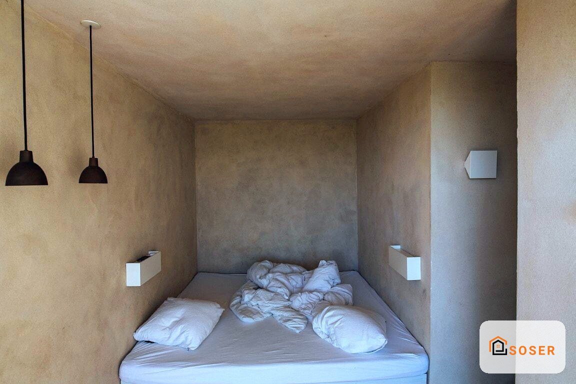 Camera da letto minimal con letto singolo, pareti in cartongesso greige e lampade a sospensione nere