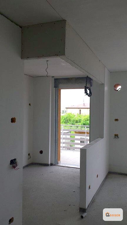 Interno di appartamento in fase di ristrutturazione con pareti in cartongesso bianco e porta d'ingresso aperta