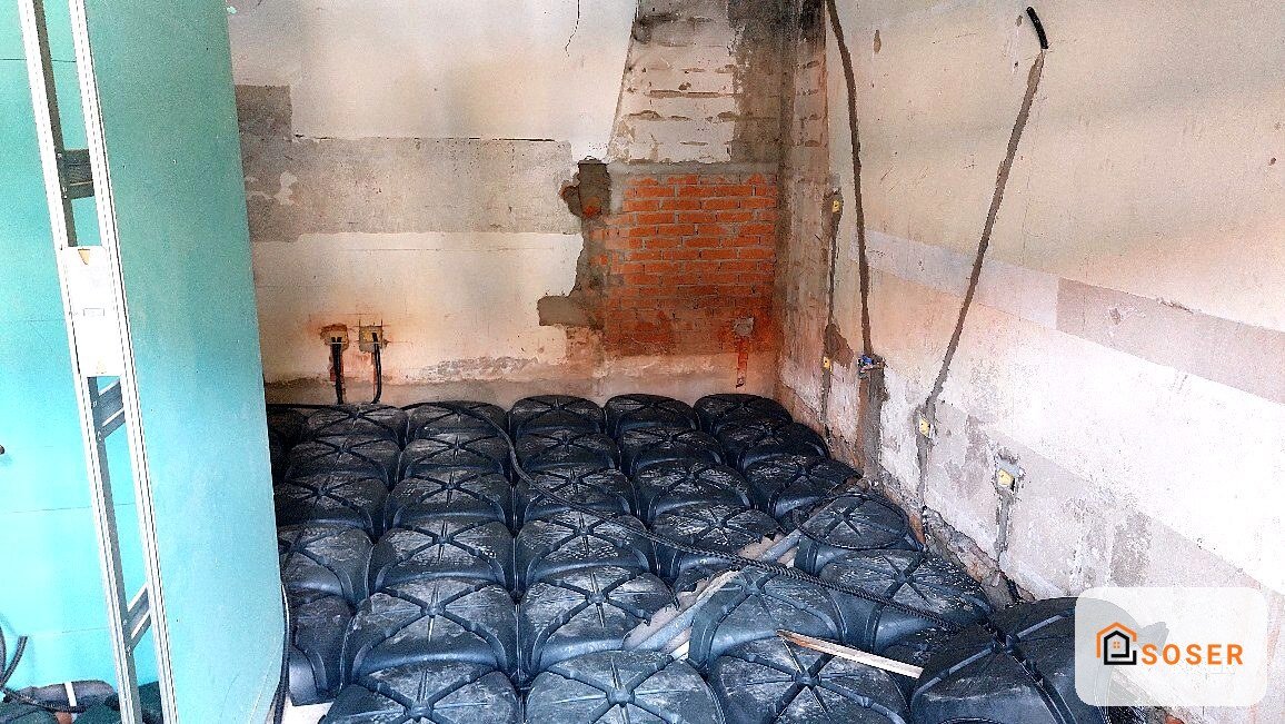Cantiere di ristrutturazione con sacchi neri impilati e pareti in mattoni rossi e intonaco