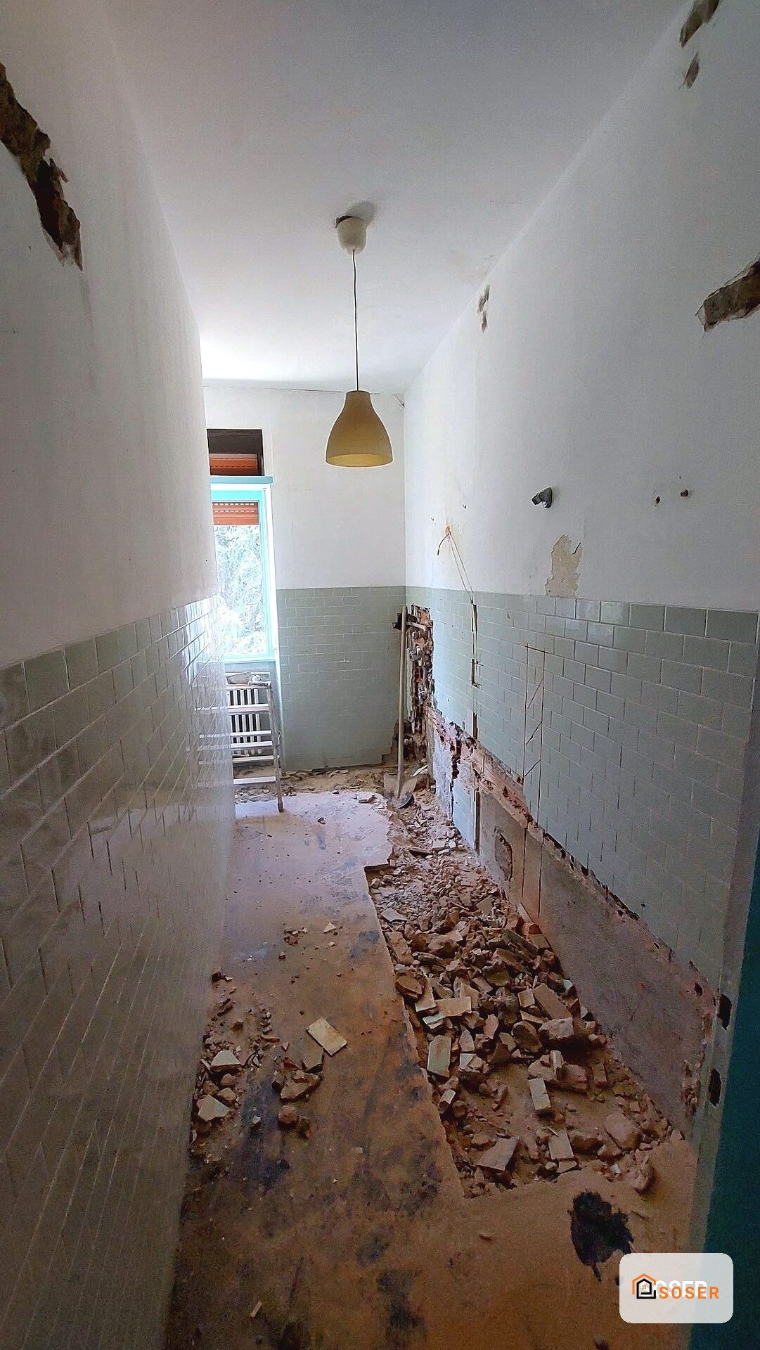 Stanza in demolizione con pareti danneggiate e soffitto crollato, pronta per ristrutturazione
