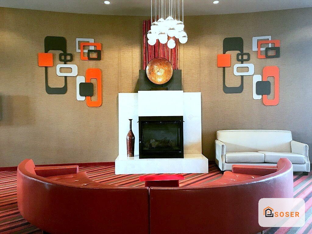 Soggiorno moderno con divano rosso curvo, pareti beige, pannelli decorativi arancioni e camino bianco