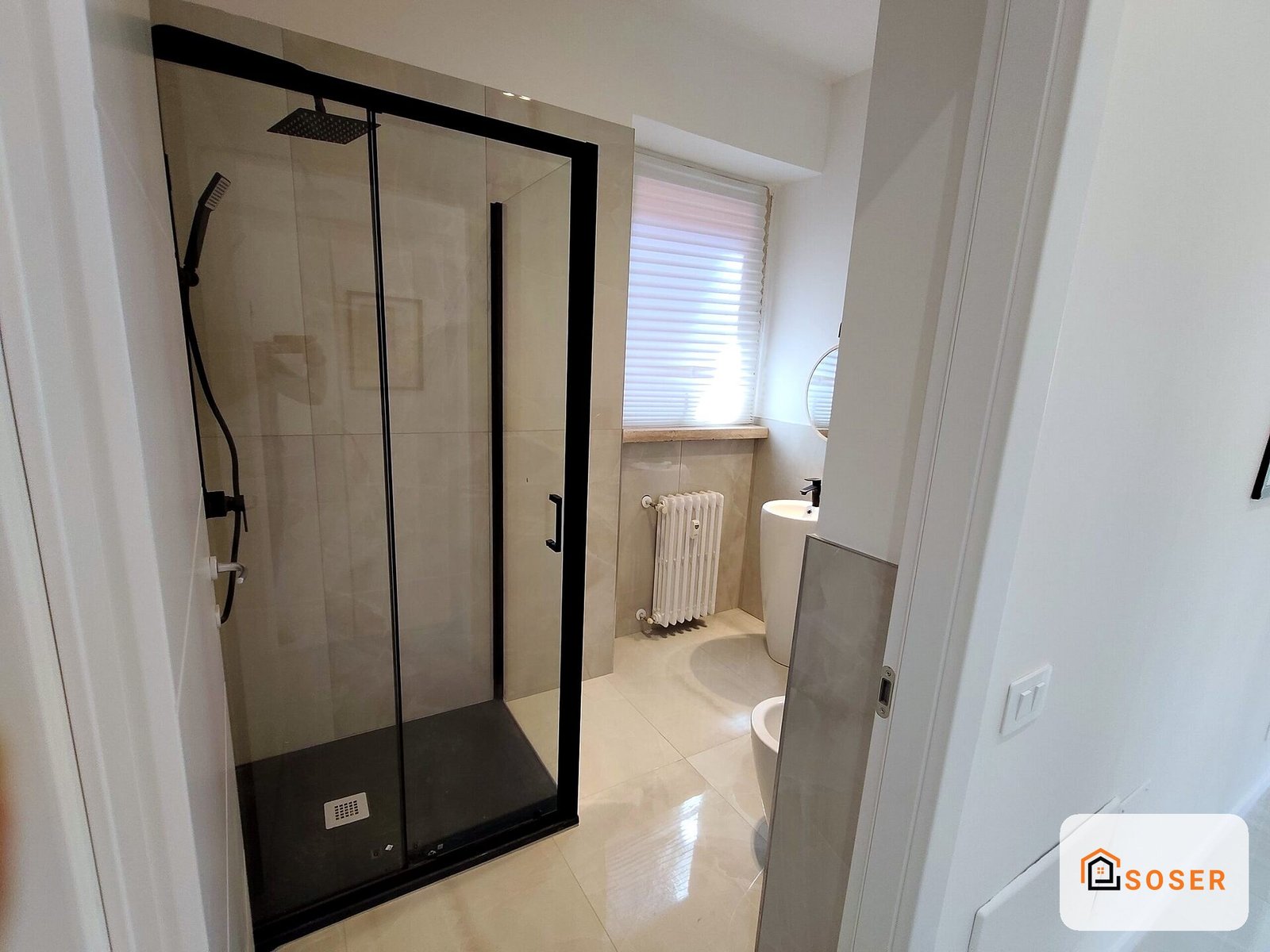Bagno moderno con doccia in vetro temperato con profili neri e pavimento in gres porcellanato beige