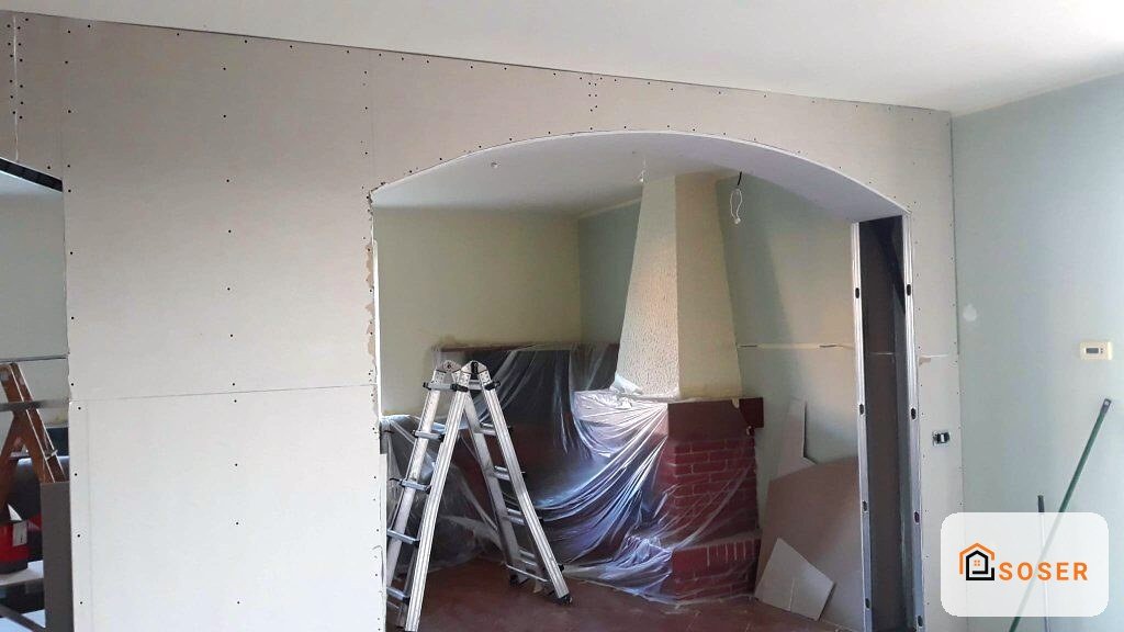 Interno in corso di ristrutturazione con cartongesso, scala e materiali protetti da teli plastici