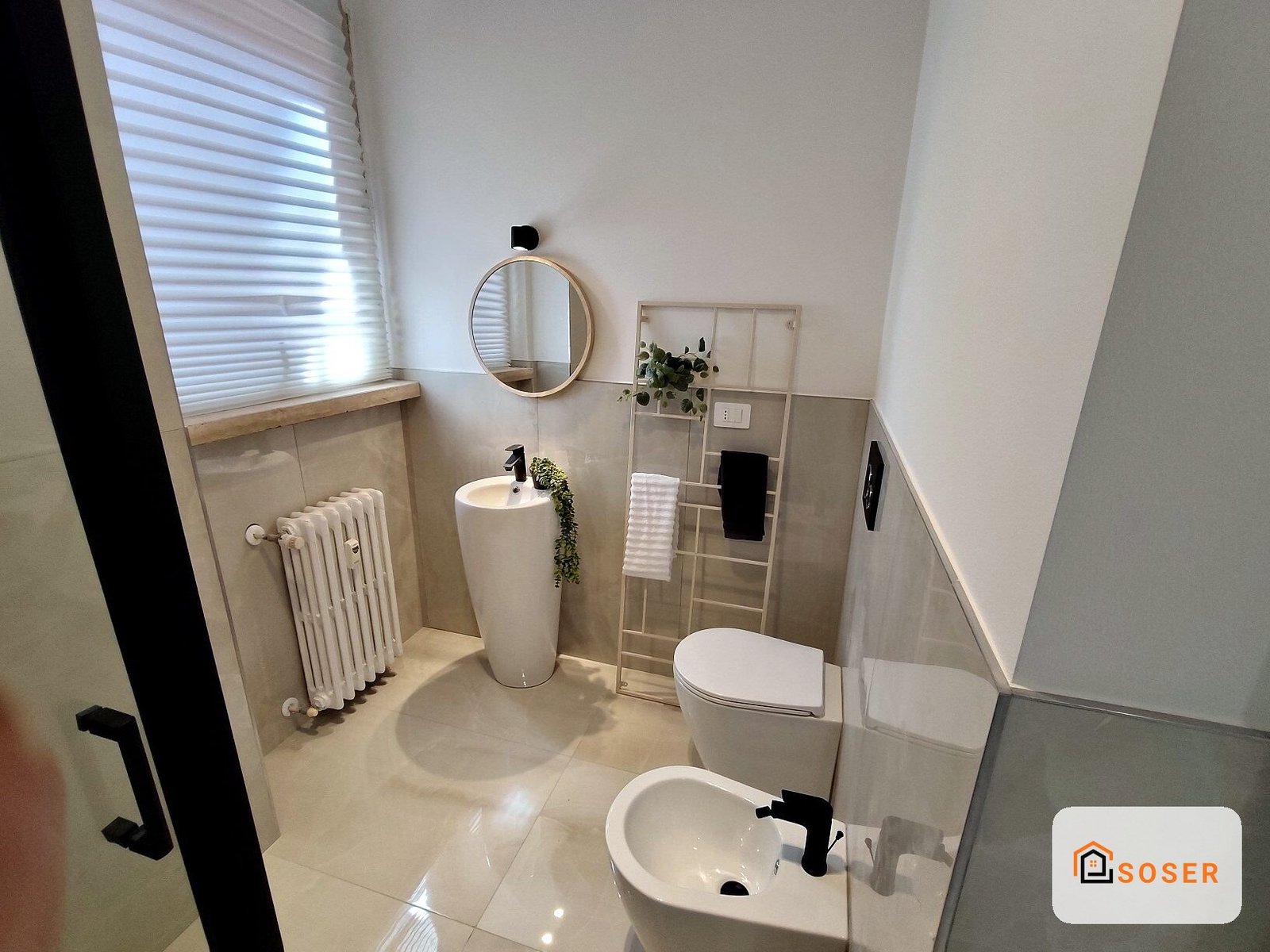 Bagno moderno ristrutturato con pavimenti in gres porcellanato, lavabo sospeso nero, specchio rotondo e doccia con box