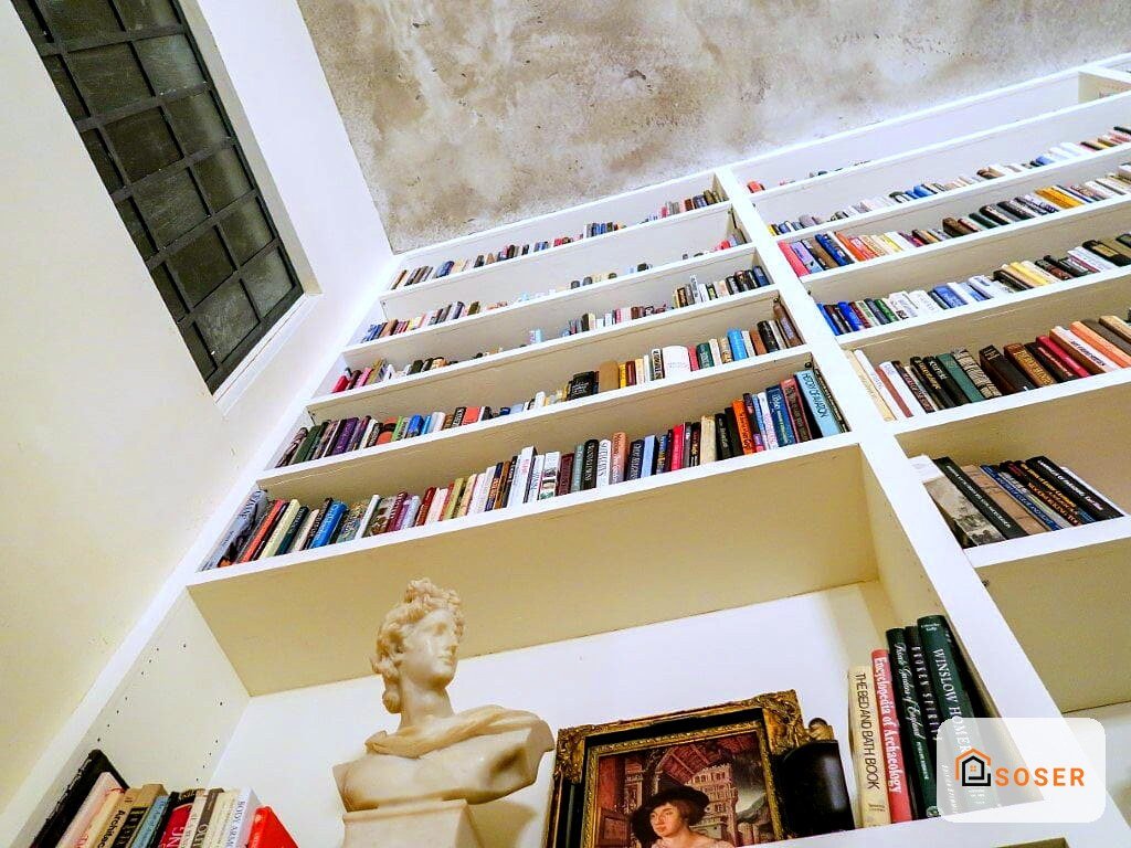 Libreria a muro in cartongesso bianco con libri colorati in una camera moderna con busto decorativo