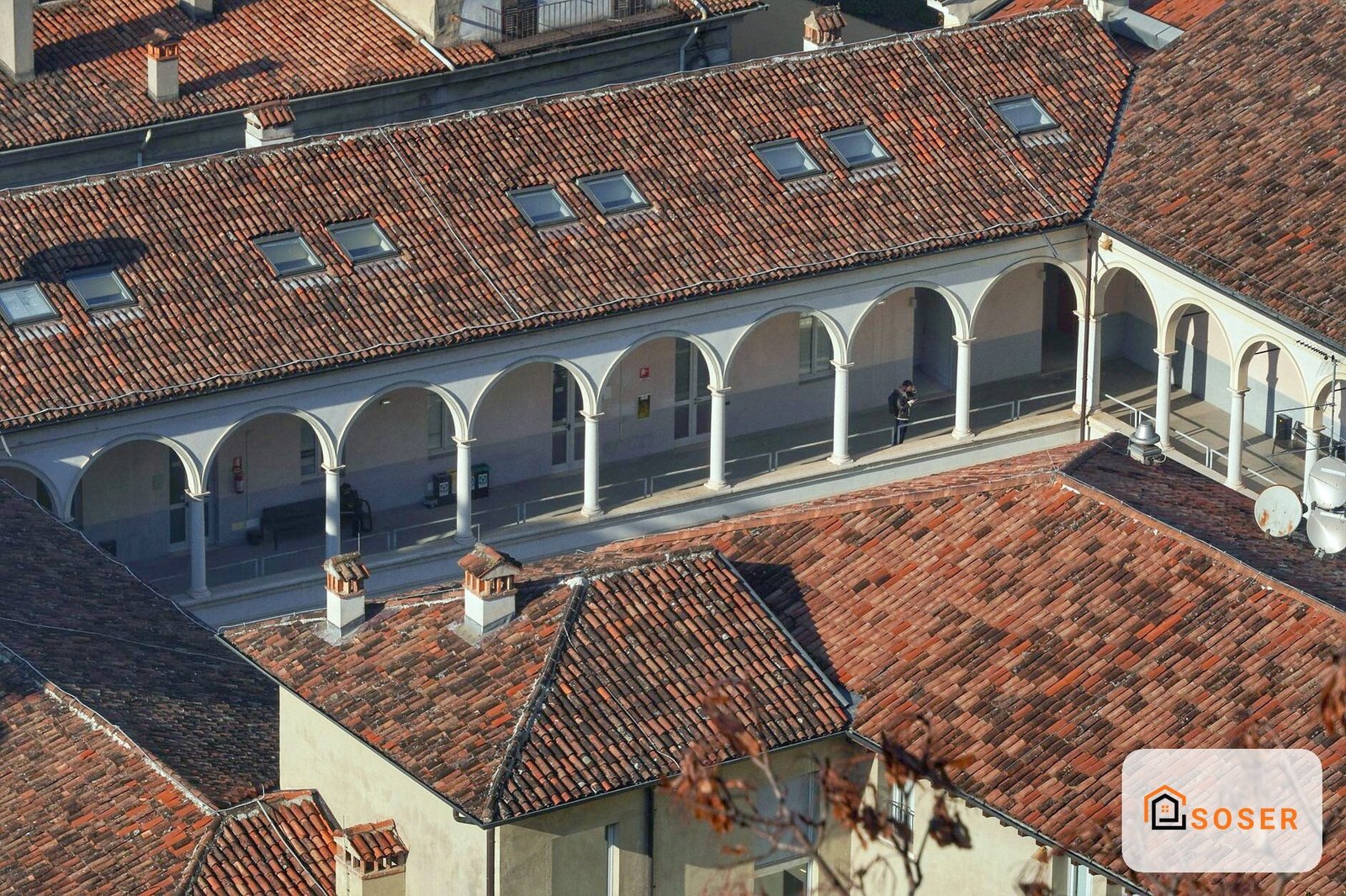 Porticato con arcate bianche e tetto in coppi rossi, vista dall'alto di una corte interna
