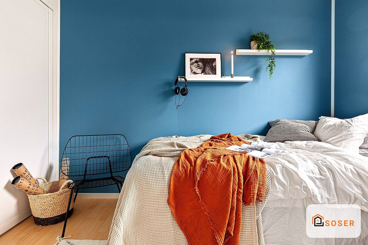 Camera da letto moderna con parete blu, letto bianco e ripiani a muro con piante