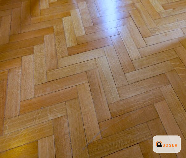 Pavimento in parquet a spina di pesce con finitura lucida in tonalità miele e naturale