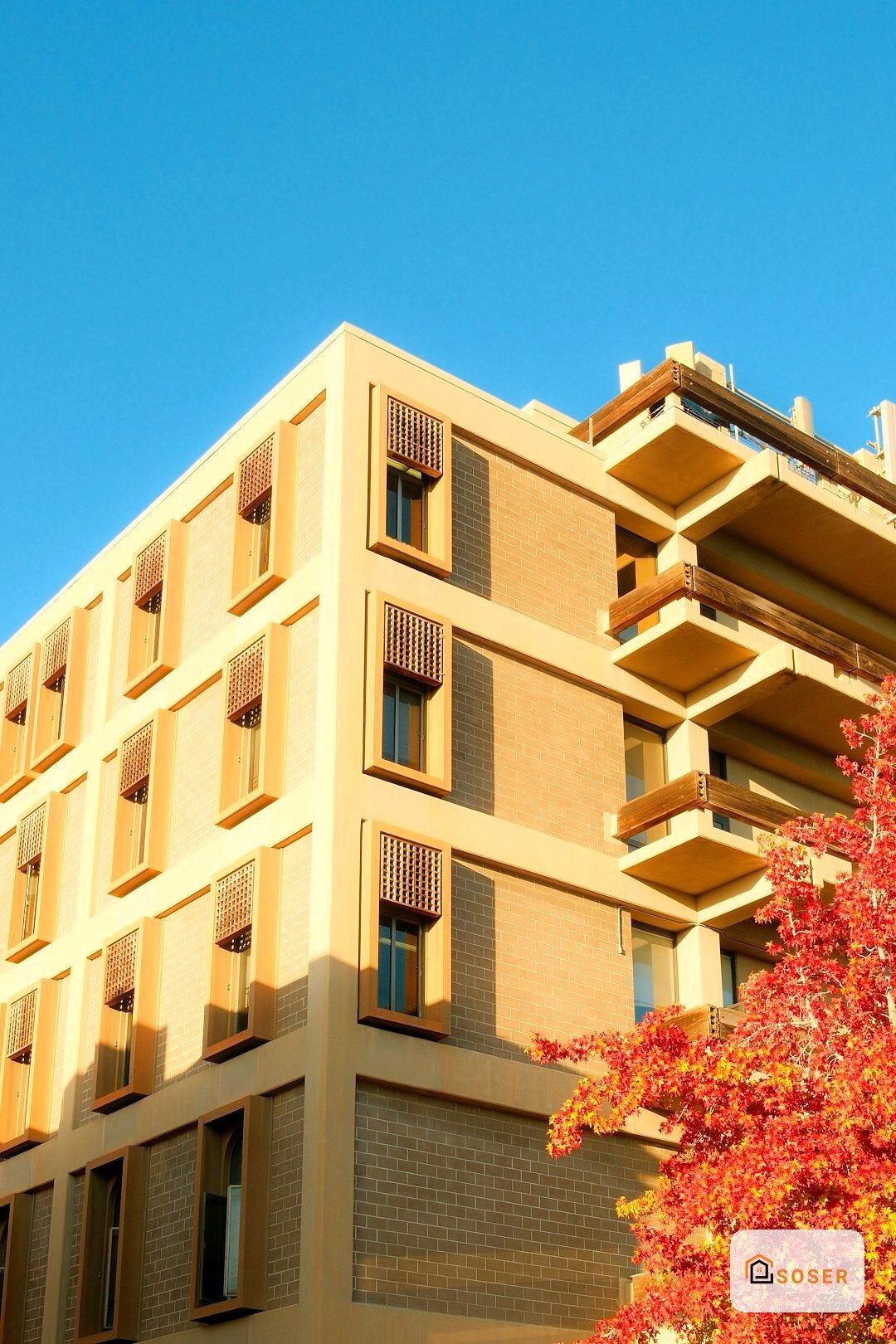 Edificio residenziale moderno con facciata in laterizio giallo e balconi in cemento sotto cielo sereno
