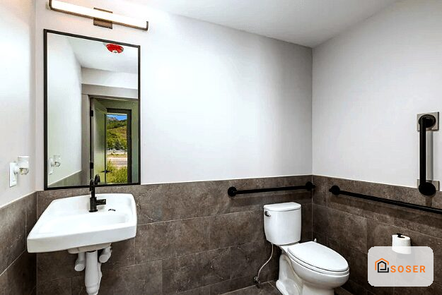 Bagno moderno ristrutturato con rivestimento scuro, lavabo sospeso bianco e specchio con cornice nera