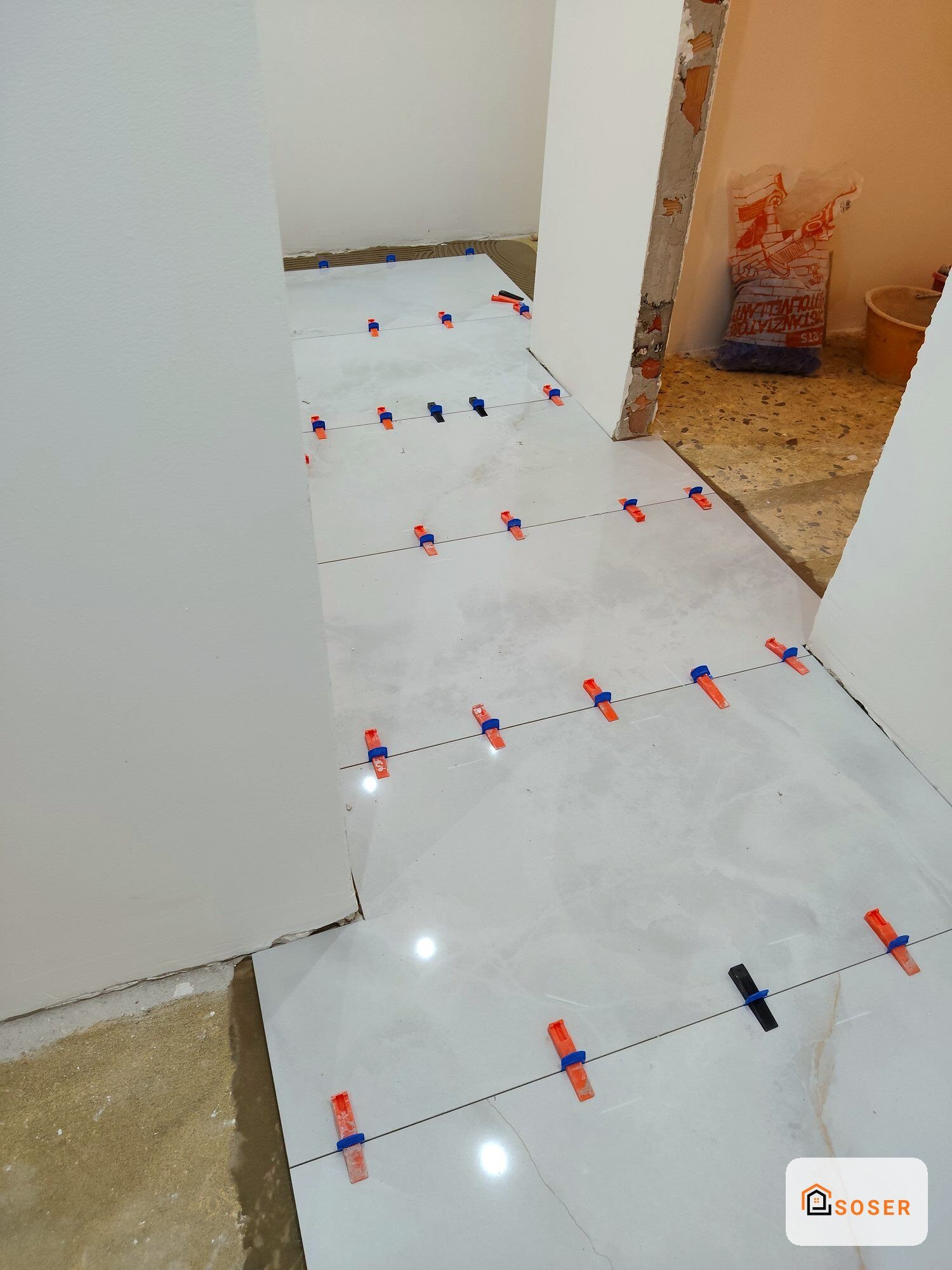 Posa pavimenti con listellature di controllo e distanziatori rossi e blu su lastre di gesso