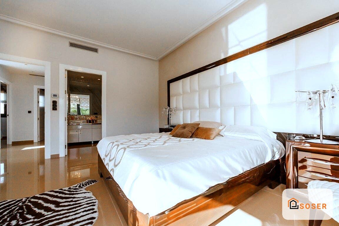 Camera da letto moderna con pavimento in marmo lucido, testata imbottita bianca e mobili in legno scuro