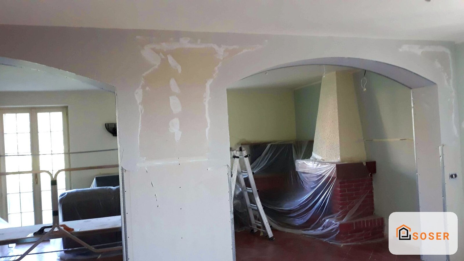 Interno in ristrutturazione con pareti in cartongesso, archi in fase di lavorazione e protezioni in plastica blu