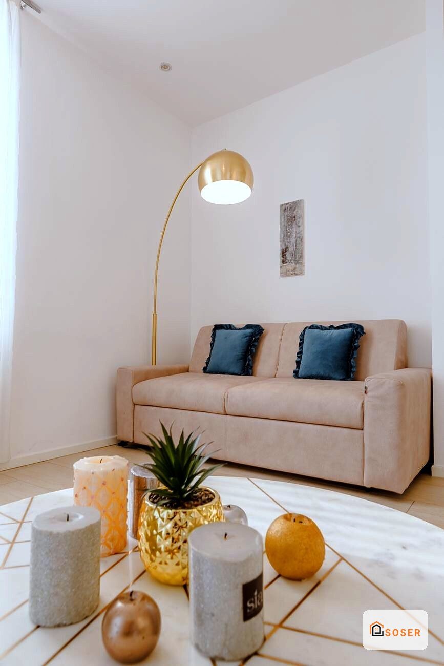 Soggiorno moderno con divano beige, lampada ad arco dorata e pavimento in marmo con dettagli geometrici