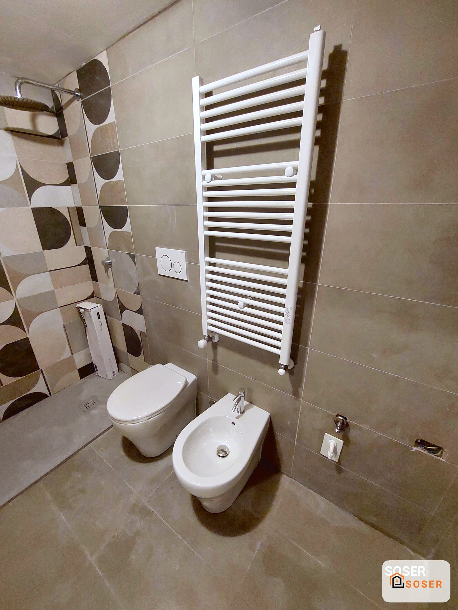 Bagno moderno con toilette, bidet e scaldasalviette bianco in ambiente piastrellato