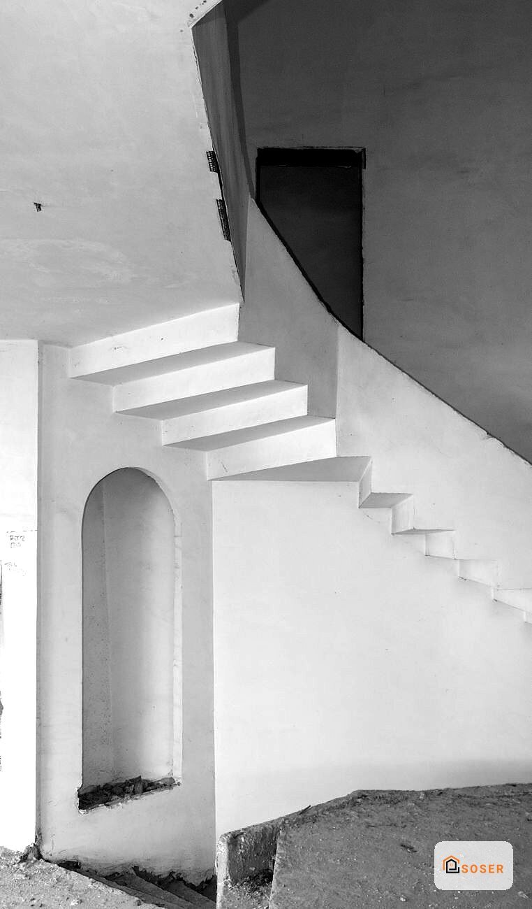Scala in cemento bianco con gradini sospesi e arco in stile minimalista