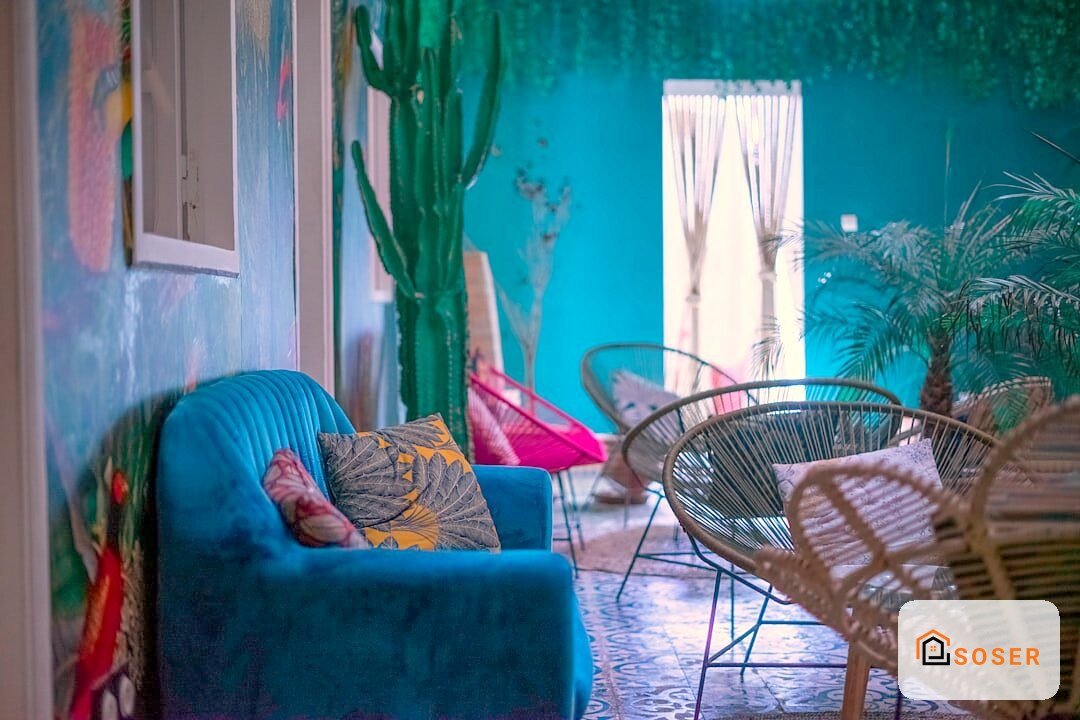 Interno moderno con parete azzurra, divano blu, sedie in rattan e piante verdi