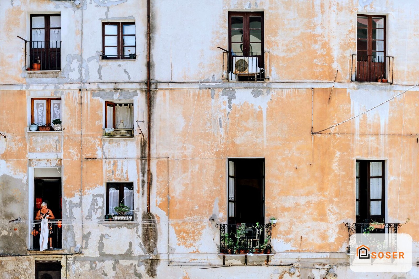 Facciata di edificio storico con intonaco deteriorato, finestre in legno e balconate in ferro