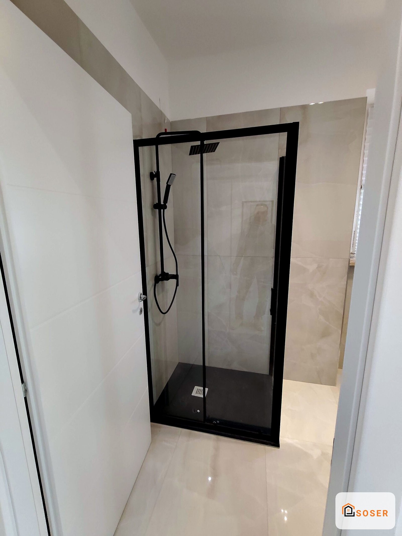 Cabina doccia con struttura nera e vetri trasparenti in bagno moderno con rivestimento bianco