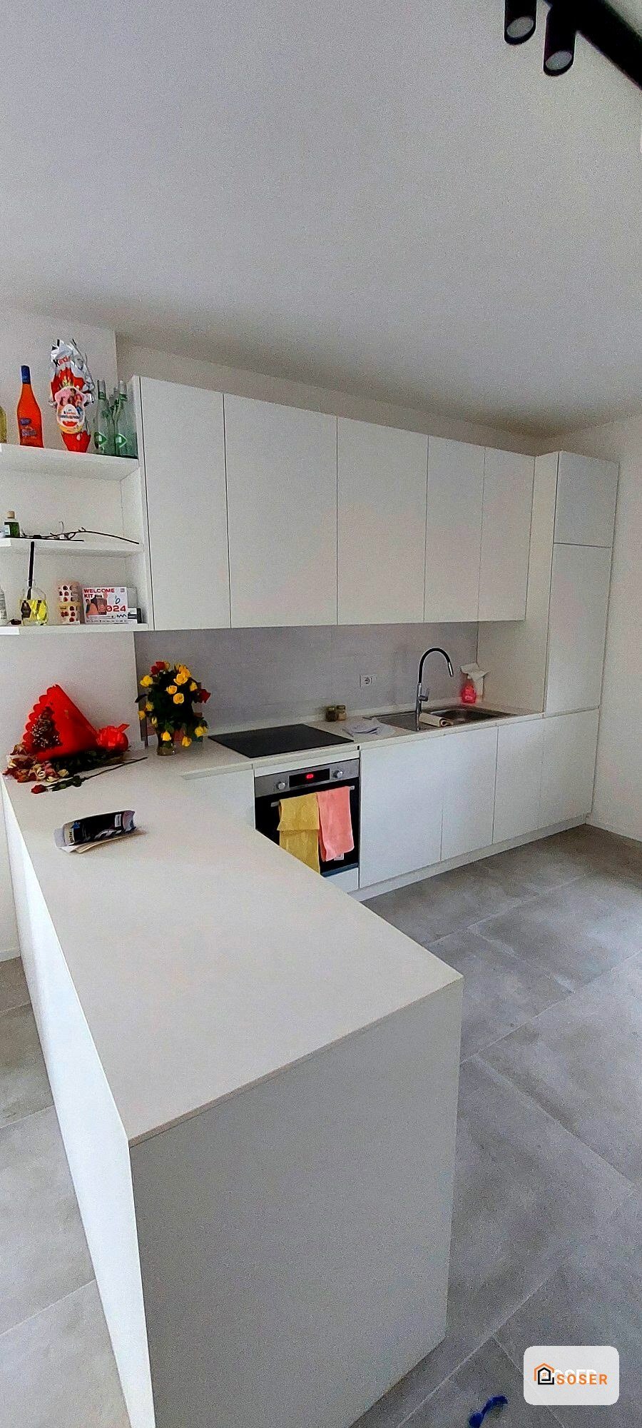 Cucina moderna bianca con isola, top in quarzo, elettrodomestici integrati e backsplash grigio