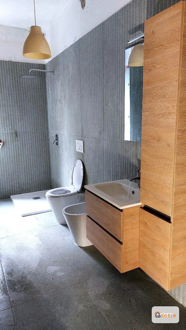 Bagno moderno con rivestimento in cemento grigio, vanity in legno e sanitari bianchi