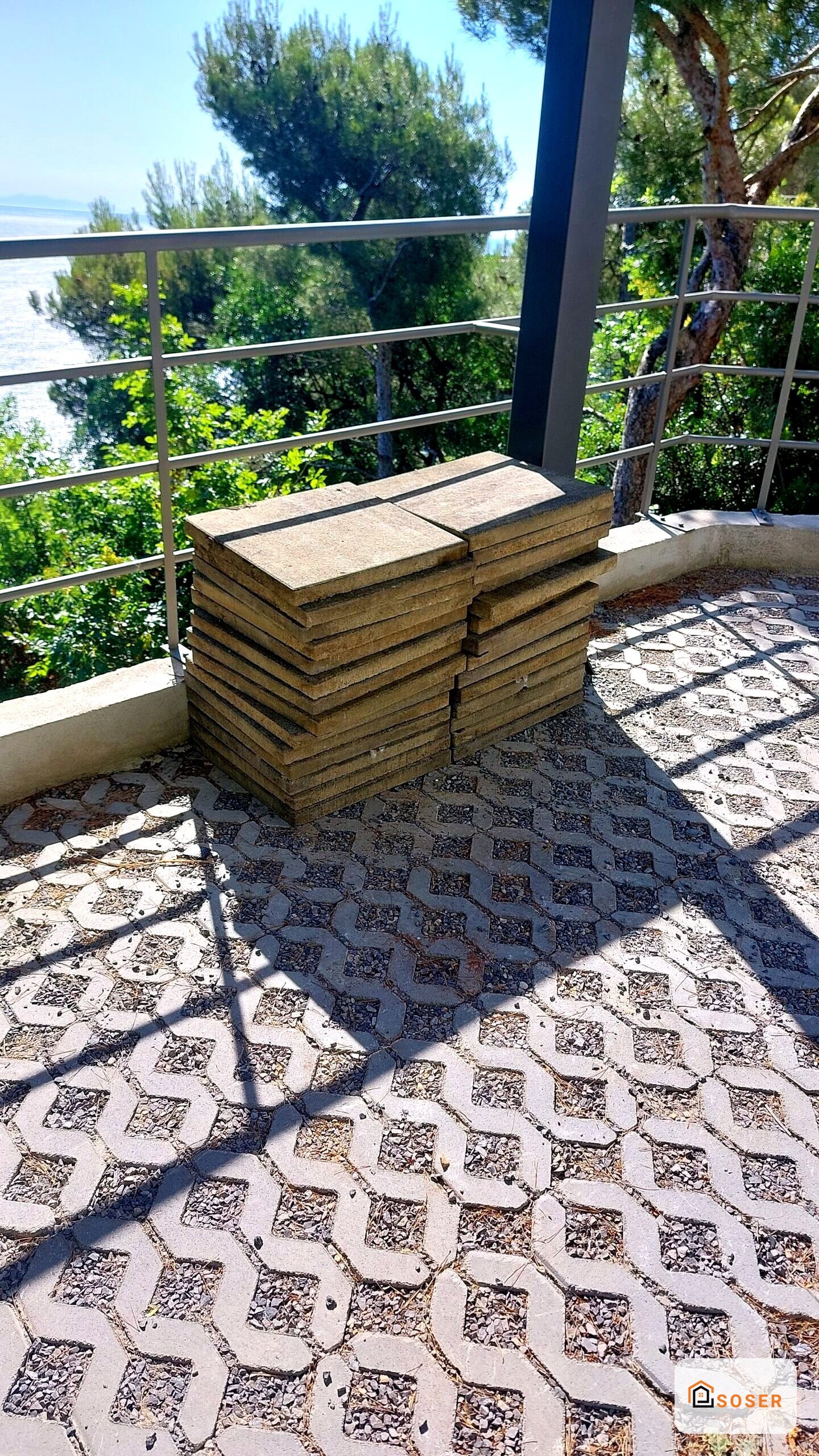 Terrazza moderna con pavimentazione a geometrici, fioriere in legno e balaustra in acciaio con vista lago